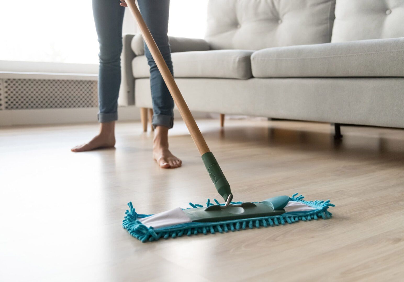 Woman housewife wash wooden laminate floor in modern living room, female cleaner housekeeper maid holding mop cleaning at home, domestic housework professional household service concept close up view