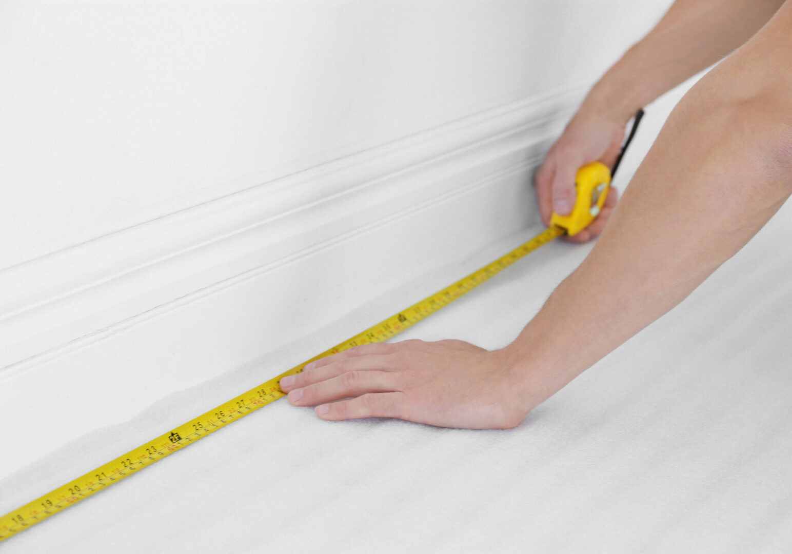 Worker with tape measure preparing to install new carpet flooring